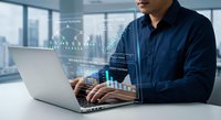 Professional businessman analyzing financial data on laptop with holographic charts and graphs in modern office environment for business analytics and investment planning.