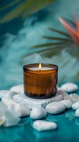 Lit amber glass candle surrounded by white stones and orchid petals on turquoise background with tropical leaves, creating serene spa atmosphere.