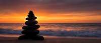Zen stone stack balanced on beach at sunset with golden sky and ocean waves creating peaceful meditation and mindfulness atmosphere for wellness concepts.