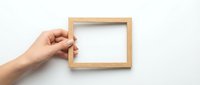 Hand holding empty wooden picture frame against white background for mockup design and creative presentation projects.