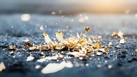 Scattered gold leaf fragments and metallic pieces on dark textured surface with soft bokeh lighting effect create luxurious artistic composition for design backgrounds.