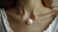 Delicate seashell pendant necklace on gold chain against feminine neckline with white lace detail, showcasing minimalist beach-inspired jewelry design for fashion and accessories.