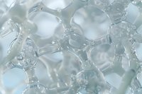 Macro view of transparent soap bubbles or water molecules creating abstract pattern with soft blue tint, showing delicate surface tension and light reflections.