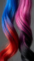 Vibrant ombre hair strands flowing with gradient colors transitioning from blue and pink to red and black, showcasing bold color techniques for salon and fashion design projects.