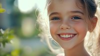 Young girl with bright genuine smile and sparkling eyes in natural sunlight, radiating joy and innocence against soft bokeh background. For lifestyle and happiness concepts.