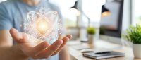 Businessman holding glowing digital wireframe sphere in hands at modern office desk, representing innovation, technology, and creative solutions for business development.