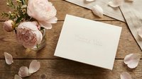 Elegant thank you card on rustic wooden table with soft pink peony flowers, perfect for wedding stationery and gratitude greeting concepts.