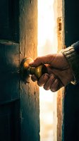 Hand opening old wooden door with brass handle revealing bright light beyond, symbolizing new opportunities and hope.