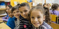 Diverse group of elementary school children smiling in classroom, representing friendship, education, and childhood development.
