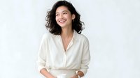 Young Asian woman with curly dark hair wearing white shirt laughing naturally while looking up, expressing joy and happiness against light background.