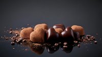 Assorted chocolate truffles and cocoa-dusted bonbons arranged on dark surface with scattered cocoa powder for confectionery, bakery, and dessert marketing.