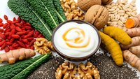 Nutritious superfood ingredients arranged around creamy yogurt bowl with turmeric swirl for healthy eating and wellness lifestyle meal planning.