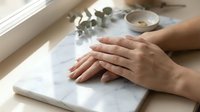 Woman hands typing on white laptop keyboard at bright workspace with coffee cup and eucalyptus branch creating productive morning work atmosphere.
