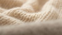Soft beige knitted wool fabric texture with natural fibers and cozy warmth for fashion design and textile projects.