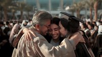 Proud parents embracing graduate daughter in cap and gown during commencement ceremony, celebrating academic achievement and family support.