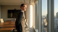 Confident businessman in suit standing by office window overlooking city skyline during golden hour, professional corporate executive leadership concept.