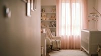 Cozy nursery room with rocking chair, crib and soft pink lighting creating warm atmosphere for baby care and parenting moments.