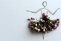 Creative floral art composition showing ballerina silhouette made with simple line drawing and pink dried flowers forming tutu dress on white background.