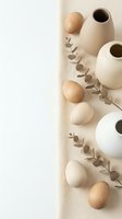 Minimalist home decor arrangement with ceramic vases, wooden spheres and eucalyptus branches on neutral beige background for interior design projects.