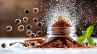 Ground coffee powder explosion with floating beans and sugar dust against dark background, aromatic composition with glass jar and fresh mint leaves.