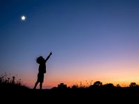 Silhouetted figure reaching toward star in twilight sky at dusk, symbolizing aspiration, dreams, and achievement for motivational and inspirational content.