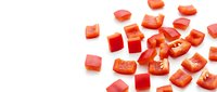 Fresh diced red bell pepper pieces scattered on white background, perfect for cooking recipes, healthy eating concepts and culinary designs.