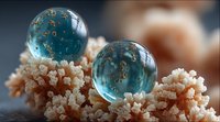Elegant blue glass spheres with gold flecks resting on delicate coral formations, creating a luxurious underwater-inspired decorative element.