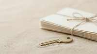 Brass key lying on neutral linen surface next to tied notebook, symbolizing access, security, and organization for business and lifestyle concepts.