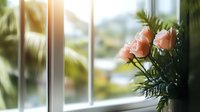 Pink roses on windowsill against soft blurred garden background create serene morning atmosphere with natural sunlight streaming through window panes.