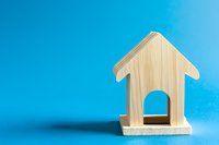 Wooden house shape on vibrant blue background with soft shadow, minimalist architectural symbol representing home, real estate, or property concept.