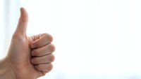 Hand showing thumbs up gesture against white background expressing approval and positive feedback for business success concepts.
