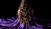 Long wavy brown hair cascading down woman's back against dark background with flowing purple silk fabric creating dramatic contrast and texture.