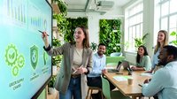 Professional businesswoman presenting green energy sustainability concepts to diverse team in modern eco-friendly office with living wall plants.