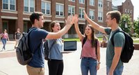 Group of diverse college students celebrating with high five on university campus courtyard surrounded by brick academic buildings and backpacks.