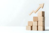 Wooden blocks stacked in ascending stair formation with upward arrow on top, symbolizing growth, progress, and business success.