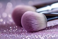 Professional makeup brush with soft pink bristles lying on glittery surface with bokeh background effect, close-up view for beauty and cosmetics industry.