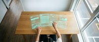 Overhead view of person working at wooden desk with digital tablet displaying financial charts and data analytics for business planning and strategy.