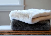 Soft plush towels neatly folded and stacked on wooden surface, featuring contrasting white and dark gray colors, creating minimalist bathroom decor composition.
