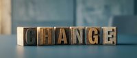 Wooden letter blocks spelling CHANGE on modern office desk surface for business transformation and personal development concepts.