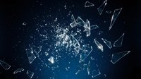 Shattered glass fragments exploding with dynamic motion against dark blue background. Broken crystal pieces scattered in dramatic destruction pattern.