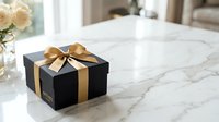 Luxury black gift box with golden ribbon bow on marble surface, elegant present for holidays, birthdays, and special occasions.
