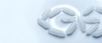 White oval pharmaceutical tablets and capsules arranged on a clean surface for healthcare, medicine, and wellness concepts.