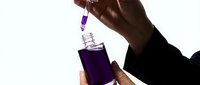 Laboratory scientist conducting chemical analysis with purple liquid sample using dropper for research and testing procedures.