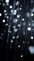 Glowing white bokeh lights on dark background with vertical lines creating magical atmosphere. Suitable for abstract backgrounds and festive designs.