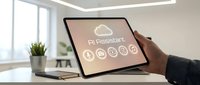 Professional using tablet displaying AI assistant interface with cloud computing icons in modern office workspace for business technology solutions.