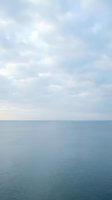 Serene seascape with calm ocean waters and soft cloudy sky, suitable for backgrounds, travel websites, and peaceful nature compositions.