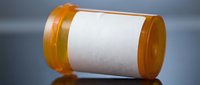 Empty prescription medication bottle lying on side with white label for pharmacy and healthcare concepts.
