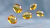Floating golden vitamin D3 or fish oil capsules on blurred blue background, macro photography showing transparent gel pills with omega-3 supplements.