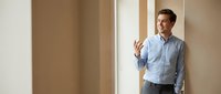 Middle-aged Caucasian male professional in business casual attire standing in doorway, gesturing while speaking. Suitable for corporate communication, business training, and office environment concepts.