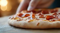 Fresh pepperoni pizza with melted cheese on crispy homemade crust, extreme close up macro shot showing texture and toppings in warm ambient lighting.